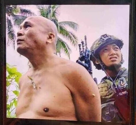 Domingo Compoc (Ka Silong), is shown under the custody of a soldier of the 47th IB, shortly after he was arrested in Bilar, Bohol on February 23. He was later subjected to torture and executed by soldiers.