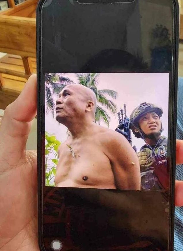 Domingo Compoc (Ka Silong), is shown under the custody of a soldier of the 47th IB, shortly after he was arrested in Bilar, Bohol on February 23. He was later subjected to torture and executed by soldiers.